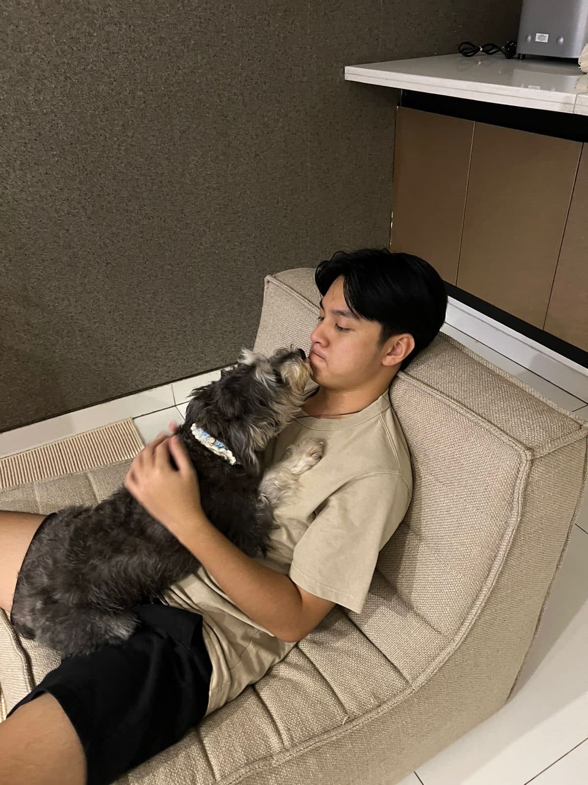 Benaya reclining on a lounge chair, nose to nose with Shiro, his grey schnauzer.
