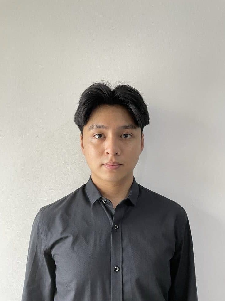 Benaya Given Janto in a dark grey button-up shirt, facing the camera against a plain wall.